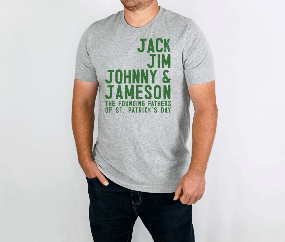 Gray whiskey founding fathers unisex t-shirt with green text listing "Jack, Jim, Johnny & Jameson, The Founding Fathers of St. Patrick's Day" worn by male model