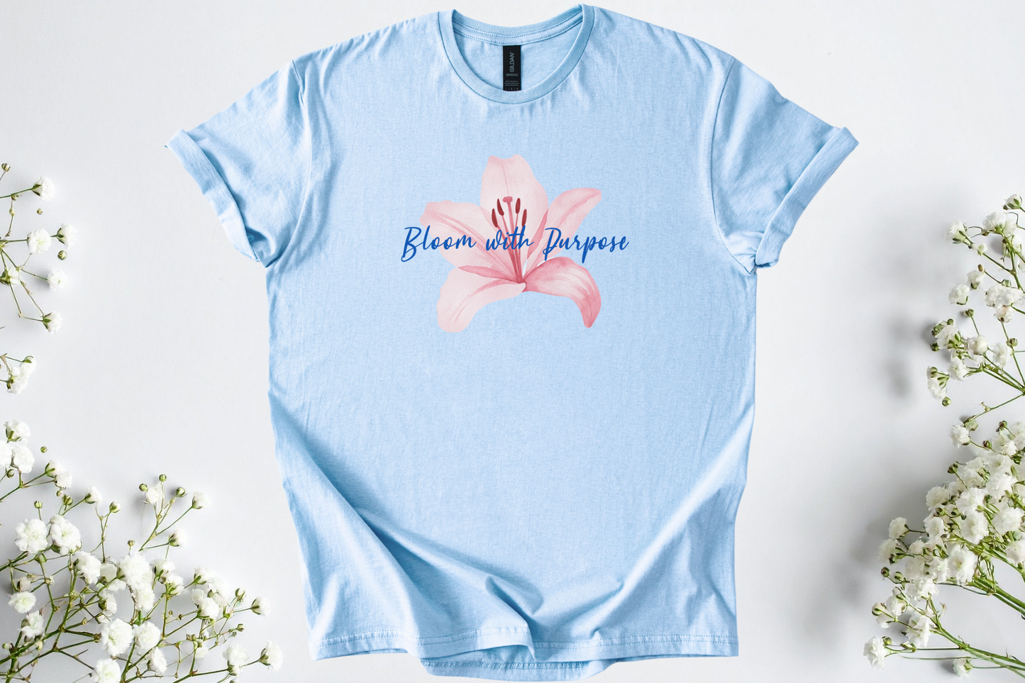 Light blue Gildan Softstyle Unisex Shirt featuring a pink flower and "Bloom with Purpose" motivational text.