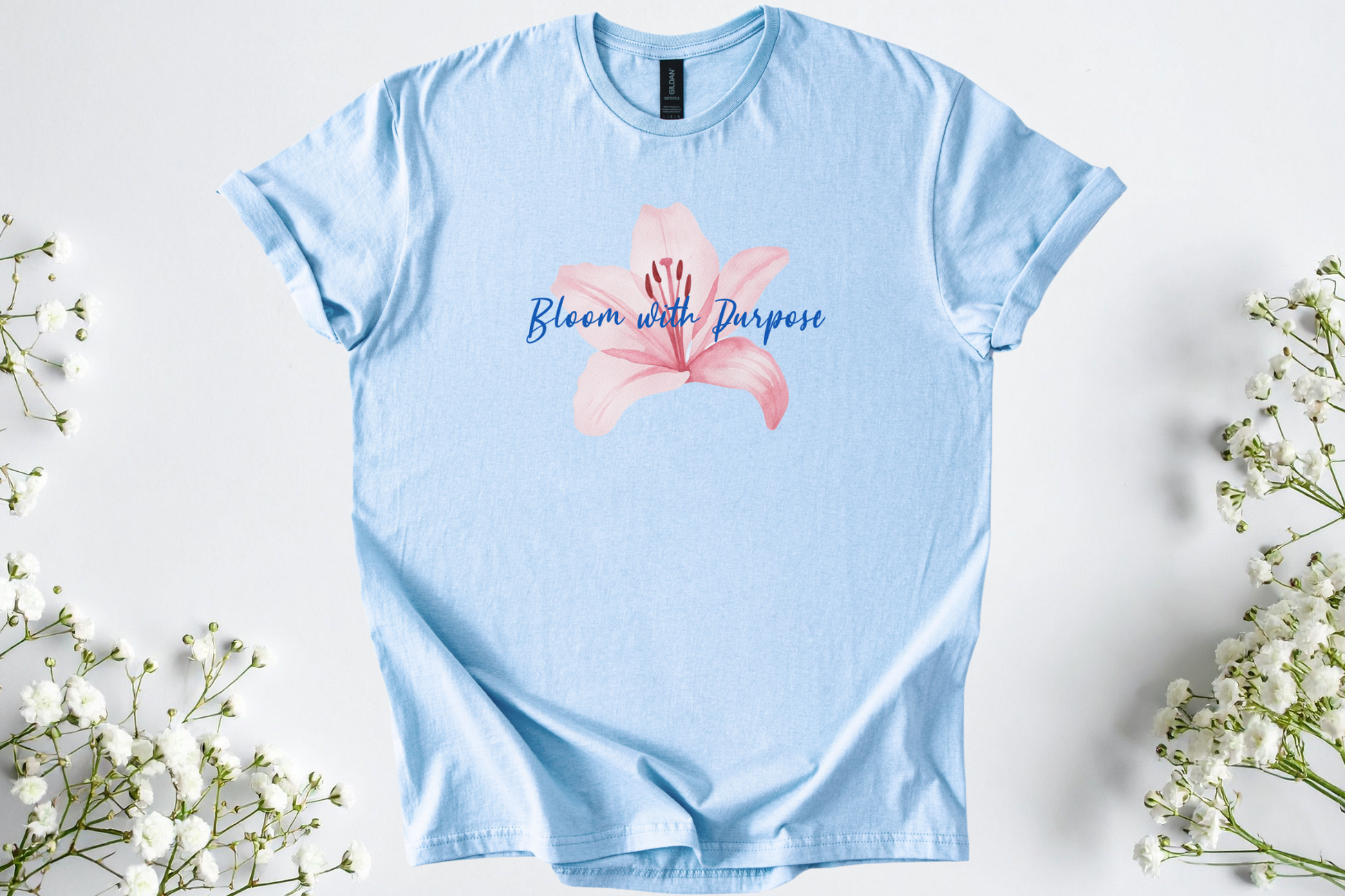 Light blue Gildan Softstyle Unisex Shirt featuring a pink flower and "Bloom with Purpose" motivational text.