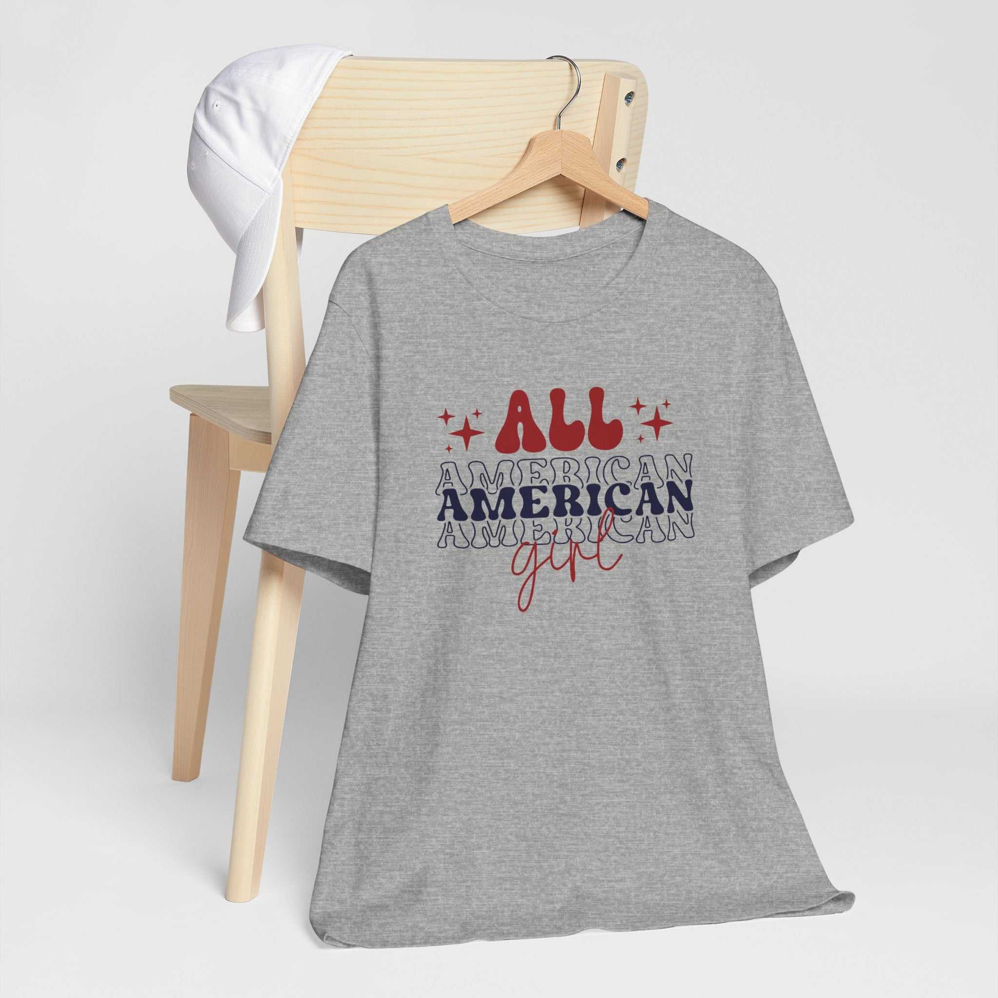 All American Girl Independence Day T-Shirt with red, white, and blue graphics on a chair.