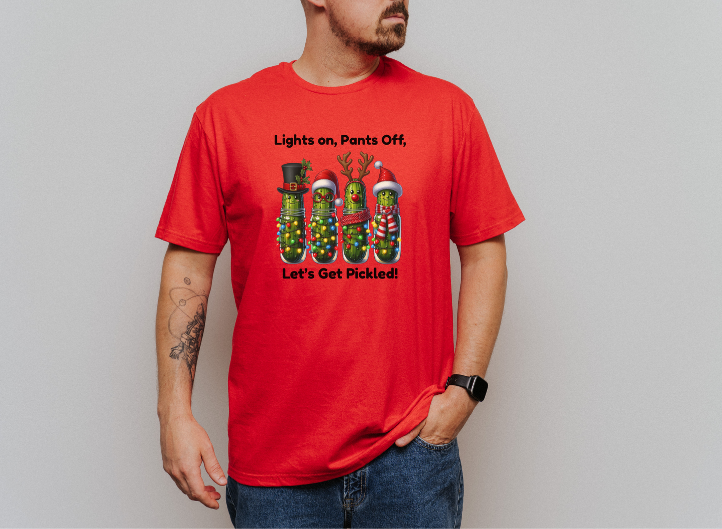 Men's red holiday T-shirt with four pickles decorated in Christmas lights and hats, featuring "Lights on, Pants Off, Let's Get Pickled!" festive design