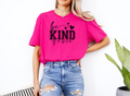Woman wearing bright pink "Be Kind of a Bitch" softstyle t-shirt with black bold text and hearts, paired with ripped blue jeans