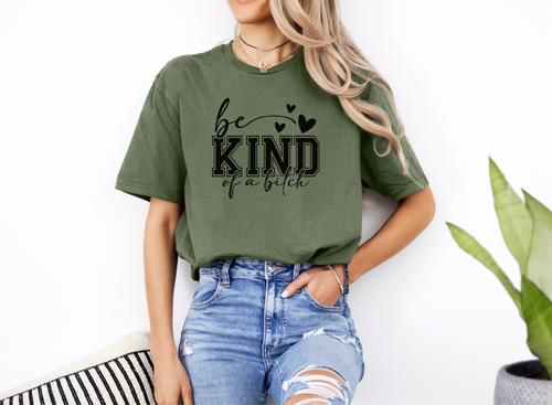 woman wearing olive green Be Kind of a Bitch softstyle t-shirt with black text and hearts, paired with ripped blue jeans
