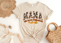 Beige softstyle shirt with "MAMA who loves Halloween" text and autumn-themed graphics, styled with fall accessories