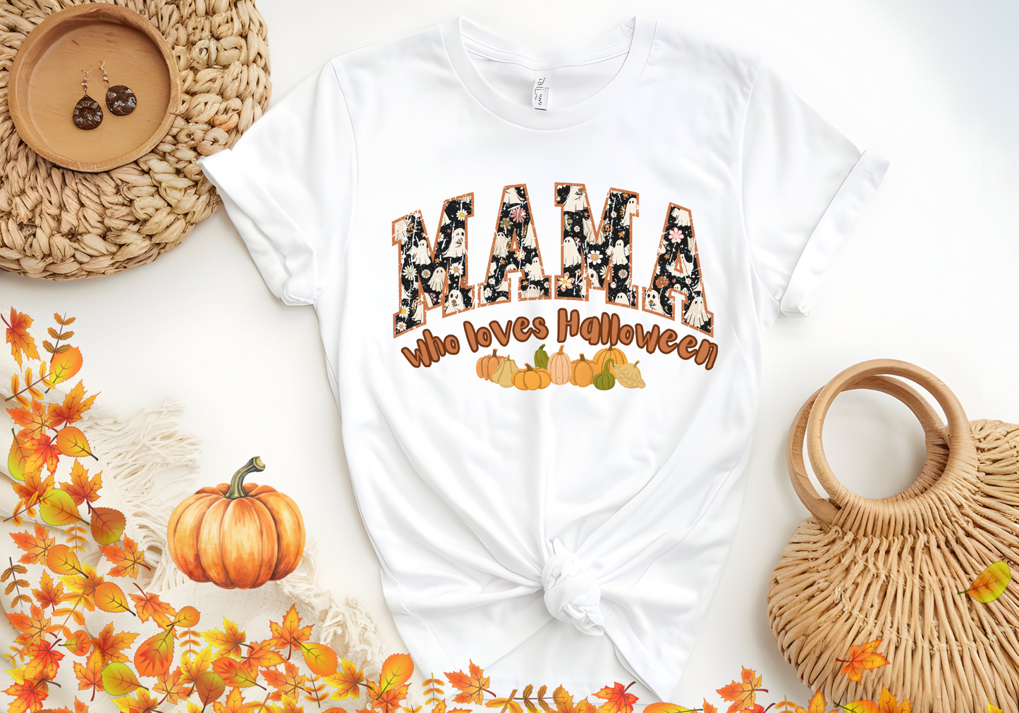 White softstyle shirt with "MAMA Who Loves Halloween" text and pumpkin design, styled for fall holidays.